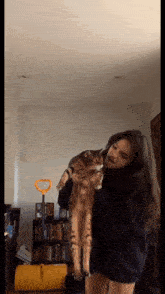 a woman is holding a cat on her shoulder in a living room
