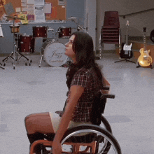 a woman in a wheelchair looks at a drum that says jazz ensemble