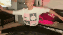 a man in a pink and white shirt is doing a split in a living room