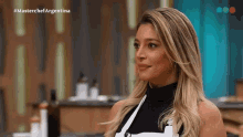 a woman in a black top and white apron is on a television show called masterchef argentina