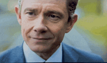 a close up of a man 's face with a blue suit and white shirt