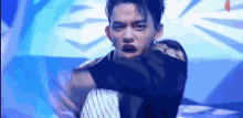 a man is dancing on a stage in front of a blue background and making a funny face .