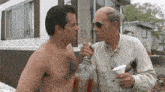 two men are standing next to each other in front of a mobile home . one of the men is drinking from a pitcher .