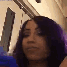 a woman with purple hair is making a funny face in a room .