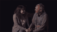 a man and a woman are sitting next to each other in a dark room and kissing .