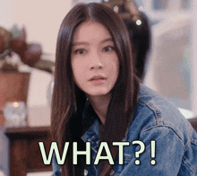 a woman in a denim jacket is making a funny face with the words what written below her