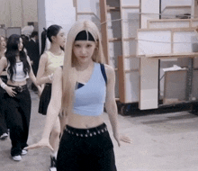 a woman with blonde hair wearing a headband stands in a room with other women