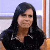a woman with long dark hair is making a sad face .
