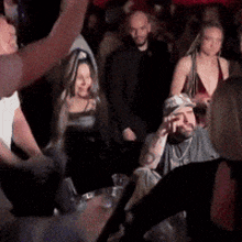 a group of people are sitting in a dark room with their hands in the air .