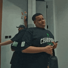 a man wearing a champion shirt is holding a cell phone