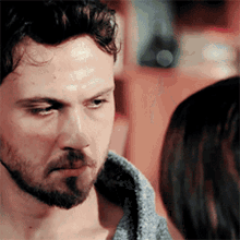 a man with a beard is looking at a woman 's face