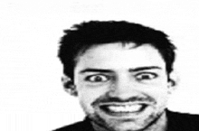 a black and white photo of a man with a beard smiling and making a funny face .
