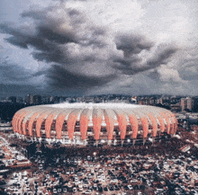 an aerial view of a stadium with a cloudy sky behind it