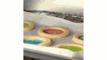 a bunch of cookies on a baking sheet with colored fillings