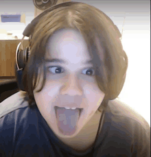 a young boy wearing headphones sticks out his tongue
