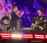 a man is singing into a microphone while another man is playing a guitar on stage .
