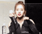 a woman is holding a microphone in front of a clear barrier with lastpang written on it