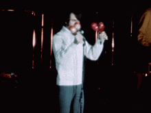 a man sings into a microphone while holding a red object in his mouth