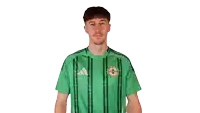 a man wearing a green adidas jersey with a cross on it