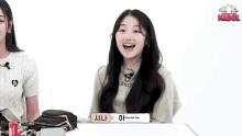 a girl is sitting at a table with her hands in the air and smiling at the camera .