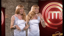 two women in white dresses are dancing in front of a massimo 's logo