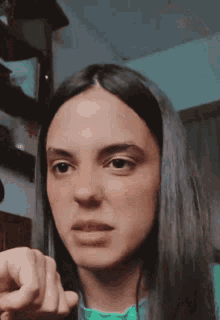a woman with long dark hair is pointing at the camera