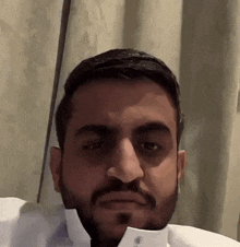 a man with a beard and a white shirt is making a face