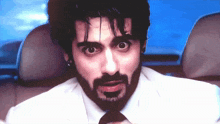 a man with a beard wearing a white suit and tie