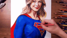 a person is drawing a woman wearing a superman costume
