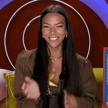 a woman in a brown striped shirt is smiling and clapping her hands