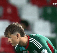 a soccer player wearing a green and red jersey with the word ssl on it