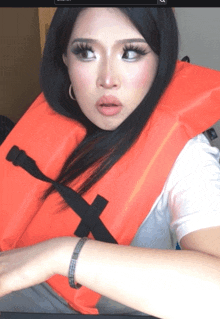a woman wearing an orange life vest with a cross on it