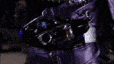 a person in a purple leather outfit has a red light on their chest with the letter s on it