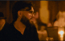 a man with glasses and a beard looks at something