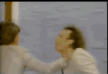 a man in a white suit and tie is dancing in front of a purple and yellow object .