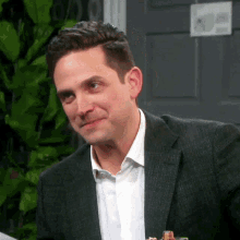 a man wearing a suit and a white shirt is smiling