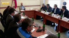 a group of men sit around a table with a sign that says subscribe on it