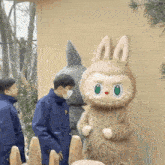 a man wearing a mask stands next to a stuffed animal in a rabbit costume .