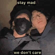 two men wearing face masks are sitting next to each other and a caption that says `` stay mad we don 't care '' .