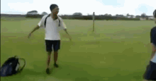 a man in a white shirt and black shorts is standing in a grassy field