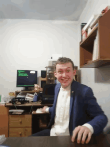 a man in a suit sits at a desk in front of a computer monitor with a green screen that says ' a '