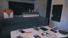 a keyboard sits on a couch in a room with a kapwing logo on the table