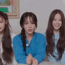 three young women are sitting at a table with their hands folded and smiling .