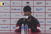 a man sitting at a table with a coca cola can and water bottle