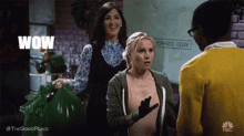 a group of people are standing next to each other and one of them is holding a green bag and says wow .