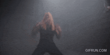 a woman with long blonde hair is standing in a dark room with smoke coming out of her eyes .