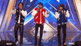three men singing on a stage with nbc written on the bottom