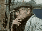 a man wearing glasses and a hat is smoking
