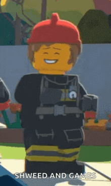 a lego fireman wearing a red helmet is smiling and holding a hose .