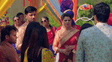 a woman in a red saree stands in front of a group of people
